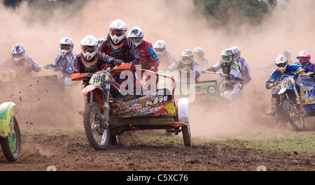 Piloti racing attraverso la polvere all'inizio di un sidecar gara di motocross Foto Stock