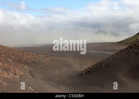 Escursionista in Emstrur Area del Laugavegur (Laugavegurinn) Sentiero Escursionistico con polvere vulcanica Storm dietro, Islanda Foto Stock