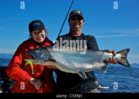 Lo sport femminile guida di pesca tenendo grande Salmone Chinook in aperto Oceano Pacifico costa occidentale dell'isola di Vancouver Foto Stock