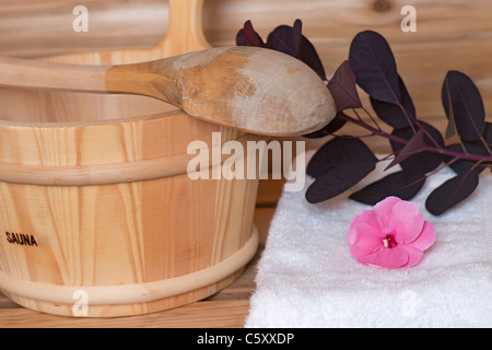 Benna con siviera attraverso di essa accanto a asciugamano con fiori all'interno di una sauna Foto Stock