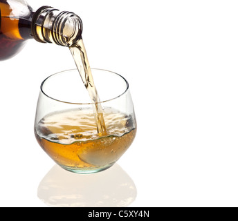 Un bicchiere di whisky che viene versato su sfondo bianco Foto Stock