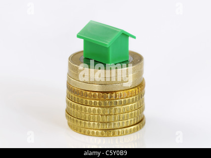 Close-up di un modello di verde casa su una pila di monete isolato su bianco Foto Stock