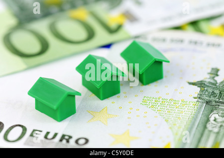 Close-up di tre green modello di casa e 100 banconote in euro Foto Stock