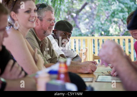 Assunto la guida dell Honduras a outdoor cafe la tabella con i turisti bianco sull'Isola di Roatan in Honduras Foto Stock