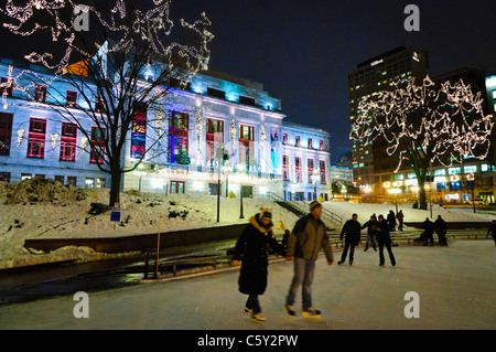 CITTÀ DI QUEBEC, Canada: I pattinatori scivolano su una pista di pattinaggio allestita di fronte all'elegante Palais Montcalm. La facciata illuminata dell'edificio storico offre uno sfondo meraviglioso per le attività ricreative invernali nel cuore del quartiere culturale di Quebec City. Foto Stock