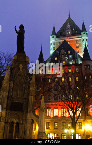 QUEBEC CITY, Canada: Il maestoso Fairmont le Château Frontenac, illuminato contro il cielo notturno, domina la città vecchia di Quebec. Le sue torrette fiabesche e i ripidi tetti di rame, spolverati di neve, creano una magica scena invernale in questo storico sito patrimonio dell'umanità dell'UNESCO. Foto Stock