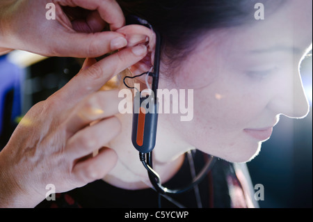 Femmina e giovane studente per audiologia indossando un apparecchio auditivo apparecchiatura per una prova nel suo orecchio destro Foto Stock