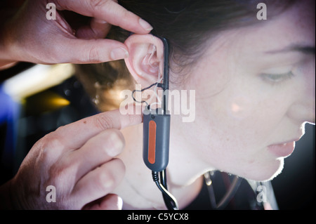 Femmina e giovane studente per audiologia indossando un apparecchio auditivo apparecchiatura per una prova nel suo orecchio destro Foto Stock