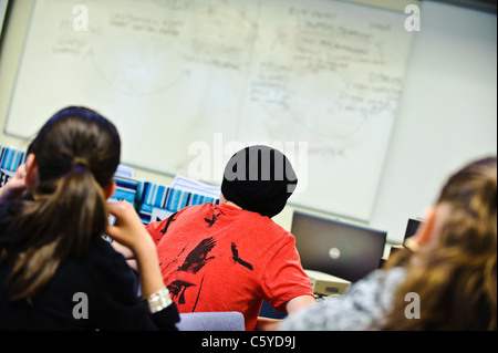 La scuola dei bambini di età compresa tra i 12-13 anni in Aula la telecamera dietro la parte posteriore della testa i bambini rivolti verso la lavagna facce non visibili Foto Stock