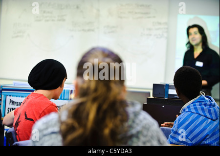 La scuola dei bambini di età compresa tra i 12-13 anni in Aula alle spalle della telecamera rivolta verso l insegnante maschio in piedi alla lavagna Foto Stock