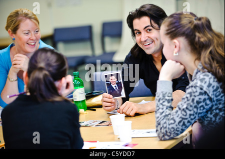 Insegnanti per adulti in aula con in mano una foto di una celebrità verso la scuola due bambini di età compresa tra 12 a 13 anni Foto Stock