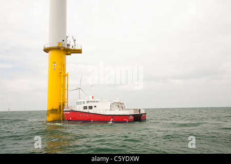 Un recipiente di alimentazione accanto ad una turbina eolica del Walney per centrali eoliche offshore project, off Barrow in Furness, Cumbria, Regno Unito. Foto Stock