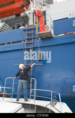 Turbina eolica lavoratori edili che viene trasferito da un cavo la posa di nave fino a riva, Cumbria, Regno Unito. Foto Stock