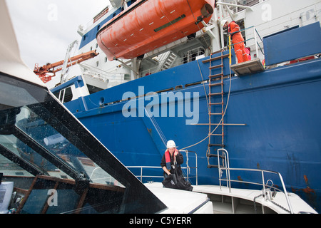 Turbina eolica lavoratori edili che viene trasferito da un cavo la posa di nave fino a riva, Cumbria, Regno Unito. Foto Stock