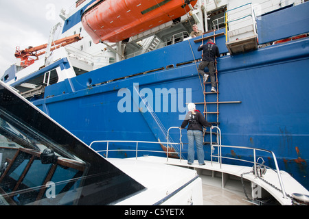 Turbina eolica lavoratori edili che viene trasferito da un cavo la posa di nave fino a riva, Cumbria, Regno Unito. Foto Stock