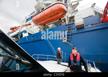 Turbina eolica lavoratori edili che viene trasferito da un cavo la posa di nave fino a riva, Cumbria, Regno Unito. Foto Stock