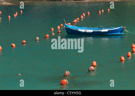 Riga barca ormeggiata in porto circondato da piccoli marcatori arancione (boe o paraurti), Vernazza, Cinque Terre, Italia. Foto Stock