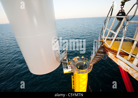 Un jack up barge abbassamento di una torre a turbina eolica il pezzo in posizione sulla Walney offshore wind farm. Foto Stock