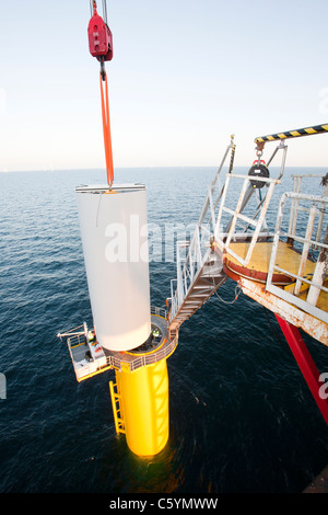 Un jack up barge abbassamento di una torre a turbina eolica il pezzo in posizione sulla Walney offshore wind farm. Foto Stock