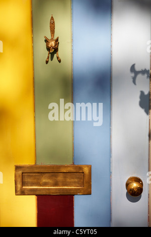 Battitalcagno in ottone, pomello e cassetta di lettere su pannello colorato di legno della porta anteriore nel Cotswolds, Gloucestershire, Regno Unito nel mese di luglio Foto Stock