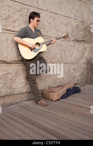 Un busker riproduce una chitarra acustica sul ponte di Brooklyn a New York City. Foto Stock