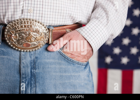 Stati Uniti d'America, Illinois, Metamora, uomo che indossa jeans e cinghia ornati in piedi nella parte anteriore della bandiera americana, metà sezione Foto Stock