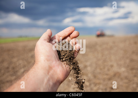 Stati Uniti d'America, Illinois, Metamora, mano che trattiene la sporcizia, campo arato in background Foto Stock