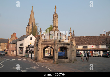 Croce di mercato con Malmesbury Abbey dietro a Malmesbury, Cotswolds, Wiltshire, Inghilterra. Foto Stock