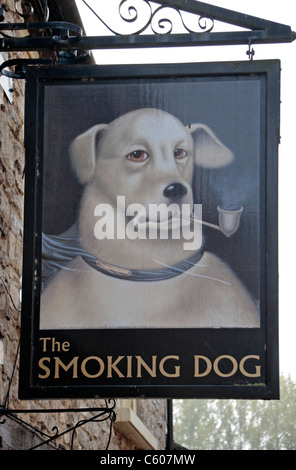 Divertente segno sopra il cane di fumare public house in Malmesbury, Wiltshire, Inghilterra. Foto Stock