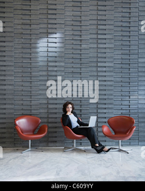 Stati Uniti d'America, New York New York City, ritratto di sorridere giovane donna utilizzando computer portatile nella hall hotel Foto Stock