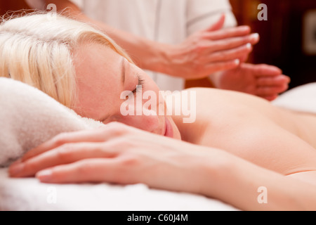 Un rilassato donna bionda ricevere un massaggio di percussione in una spa Foto Stock