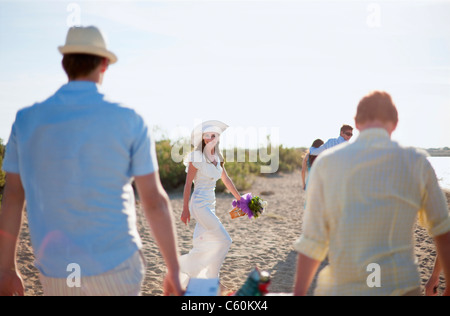 Sposa a piedi con gli amici sulla spiaggia Foto Stock