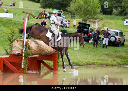 Cavallo e cavaliere saltando in acqua sulla cross-country al Festival britannico di eventing a Gatcombe Park in Gloucestershire Foto Stock