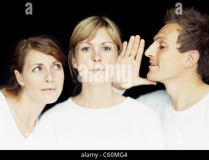 L'uomo whispering nella donna di orecchio Foto Stock