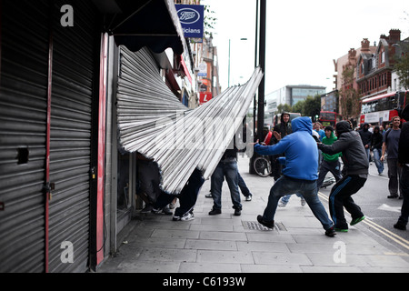 Forza di saccheggiatori hanno il loro modo in un negozio a Hackney street tumulti, Londra. Foto Stock