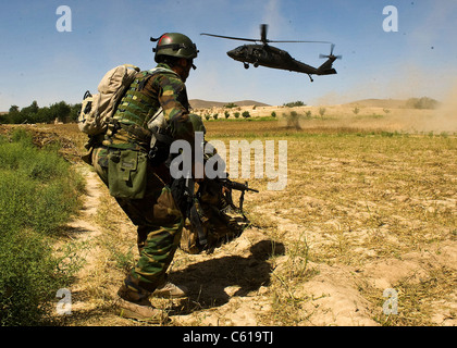 Un commando afghani le bretelle di se stesso come un UH-60 Black Hawk elicottero arriva per estrarre lui a seguito di una operazione di compensazione in quartiere Khakrez, provincia di Kandahar, Afghanistan, 31 maggio 2011. L'operazione ha causato il distacco di quattro sospetti insorti, nonché lo sfruttamento di IED e materiali per la fabbricazione di armi-dispositivo di puntamento. Il commando è assegnato all'esercito nazionale afghano di terza Commando Kandak. (U.S. Esercito foto di Sgt. Daniel P. ha scosso/rilasciato) Foto Stock