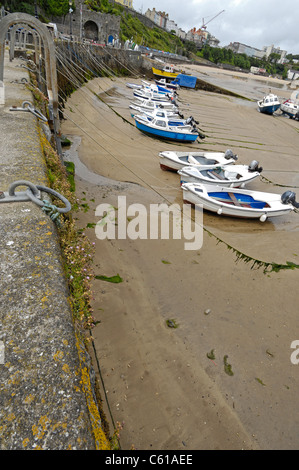 Piccole imbarcazioni legato al porto di pietra mare difese a Tenby in Galles a bassa marea. Foto Stock