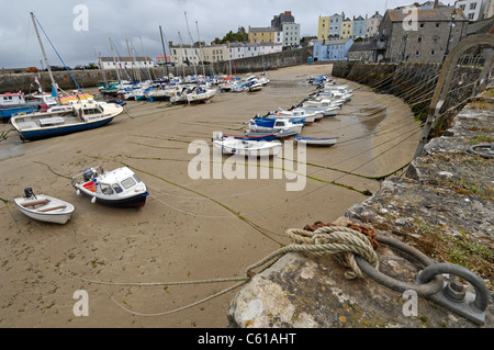 Piccole imbarcazioni legato al porto di pietra mare difese a Tenby in Galles a bassa marea. Foto Stock