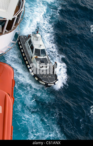 Barca pilota vicino lungo il lato di una nave crociera lungo la costa del Mar Mediterraneo vicino a Messina, Sicilia. Foto Stock