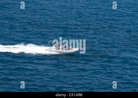 Un pontone, gomma velocità delle imbarcazioni attraverso l'acqua con la guardia costiera italiana a bordo nel Mare Mediterraneo. Foto Stock