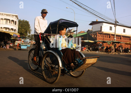 Triciclo cambogiano di risciò passeggero sulla porta passeggero donna dal mercato di Phnom Penh Foto Stock