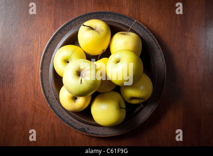 Una piastra di golden delicious visto dal di sopra su un tavolo di legno Foto Stock