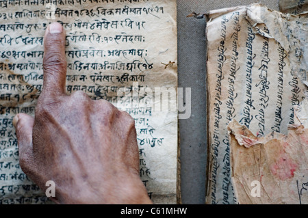 Un uomo che cerca di leggere un antico manoscritto in nepalese Foto Stock