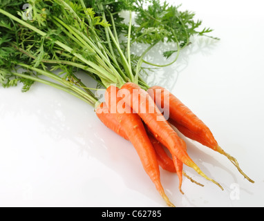 Le carote fresche con foglie verdi su sfondo bianco Foto Stock