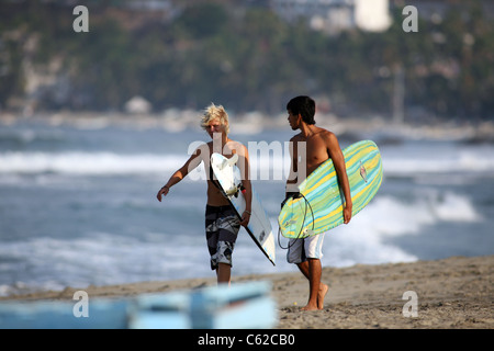 Surfers camminando lungo la famosa Zicatela spiaggia di Puerto Escondido, Messico. Foto Stock