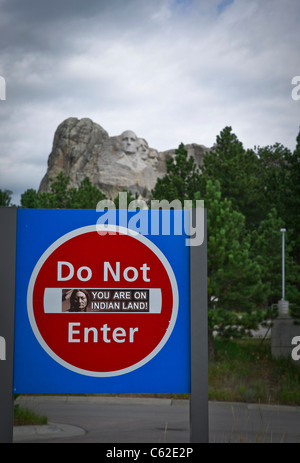 Non entrare nel cartello di un parcheggio per il Monte Rushmore con l'adesivo ti trovi sulla terra indiana con le teste dei presidenti sullo sfondo in alta risoluzione verticale degli Stati Uniti Foto Stock