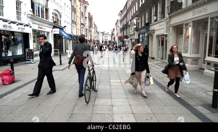 Donna con la bicicletta e la gente camminare lungo il nuovo Bond Street passato boutique per lo shopping negozi nella zona ovest di Londra Inghilterra KATHY DEWITT Foto Stock