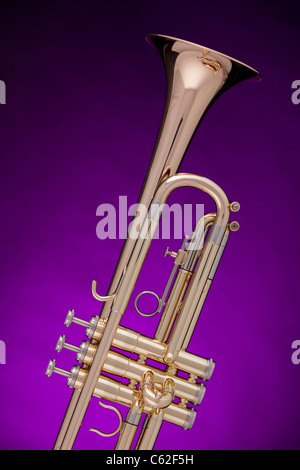 Un professional gold tromba isolata contro un faretto viola sfondo. Foto Stock