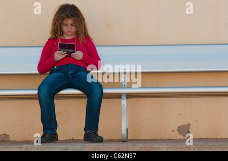 Ragazza adolescente giocando il gioco digitale sul banco di lavoro Foto Stock