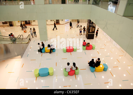 La gente seduta sui sedili di riposo in un centro commerciale per lo shopping di Hong Kong, Cina Foto Stock